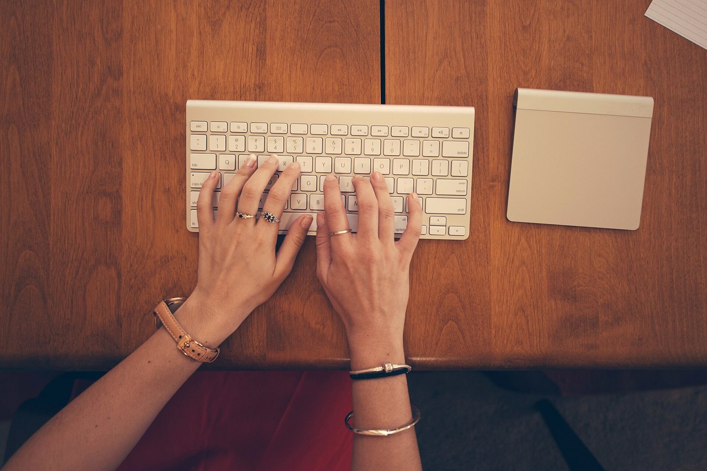 Hands typing on a keyboard at a wooden desk